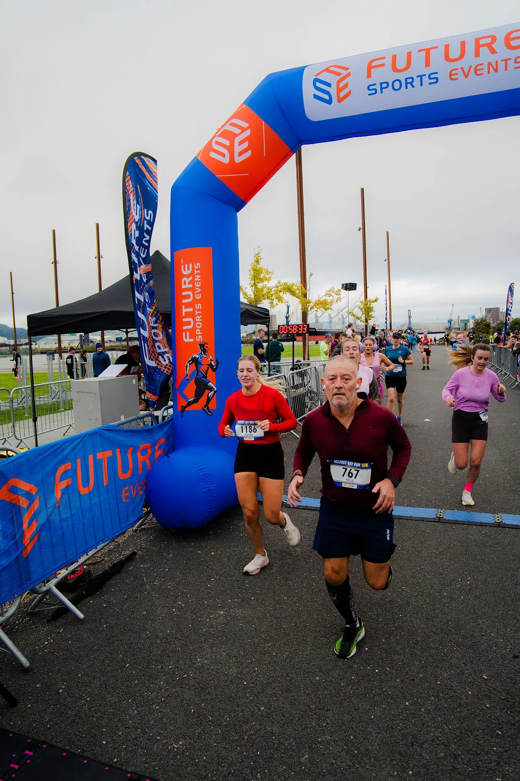 A runner crossing beneath the Future Sports finish arch in Belfast