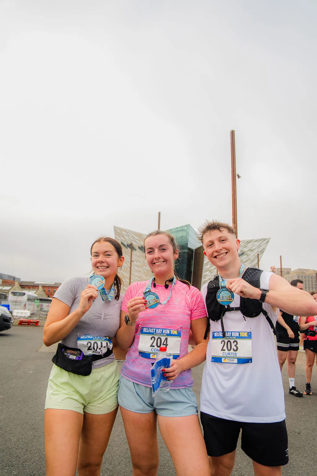 Three runners celebrating together with their medals after the Belfast Bay Run