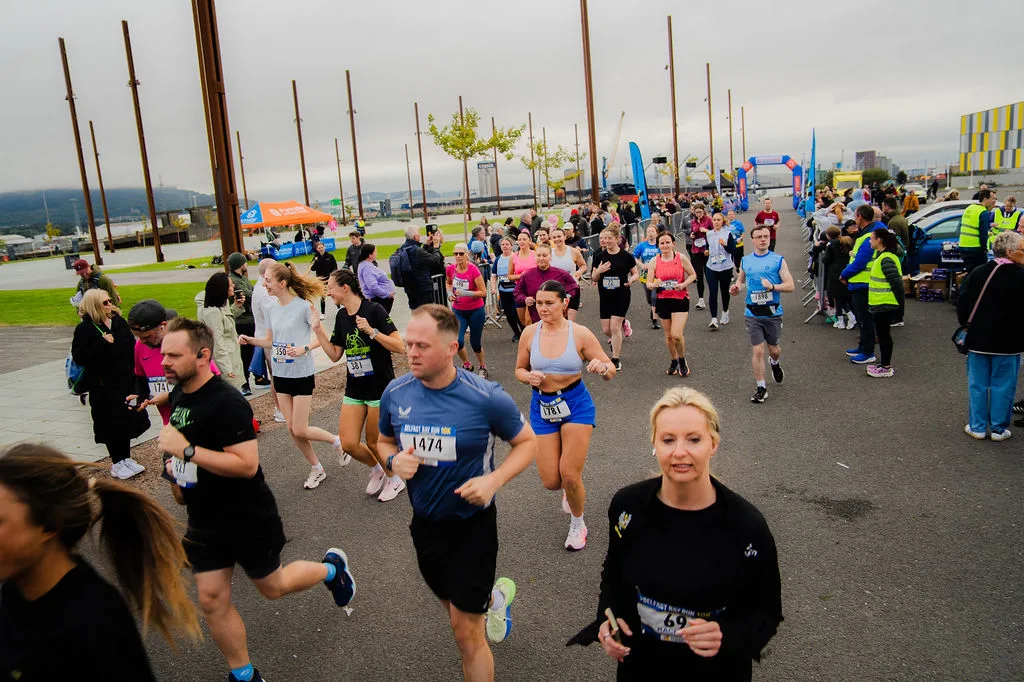 Runners smiling as they pass the camera at the Belfast Bay Run