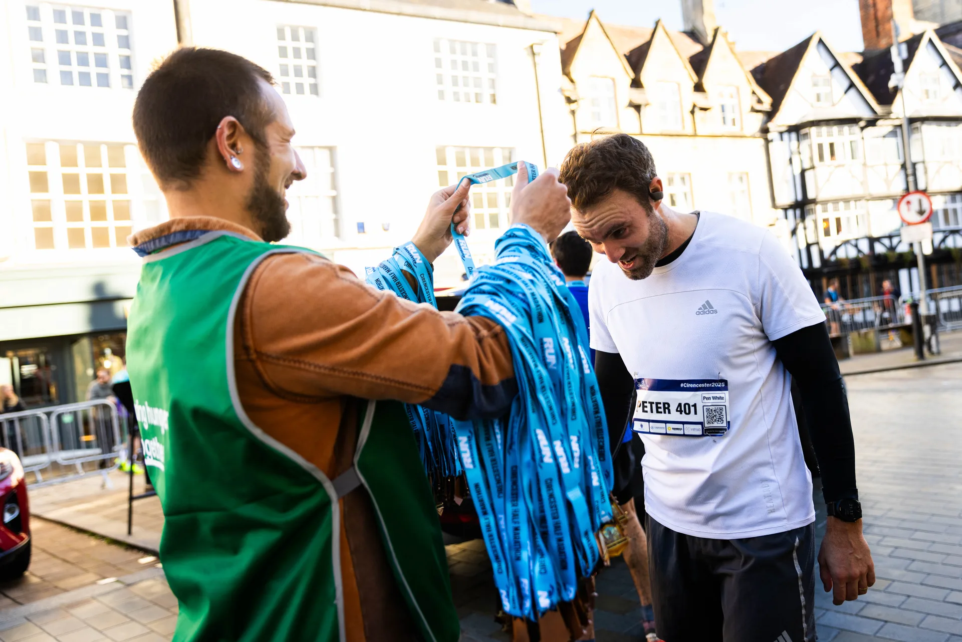 A volunteer presenting a finisher medal to a runner in Cirencester